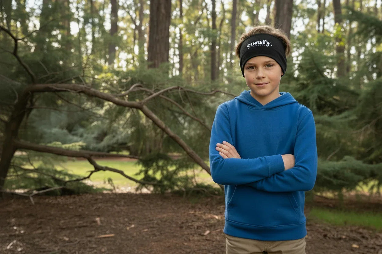 Child wearing a blue hoodie and black headband with 'empire' logo in a forest setting